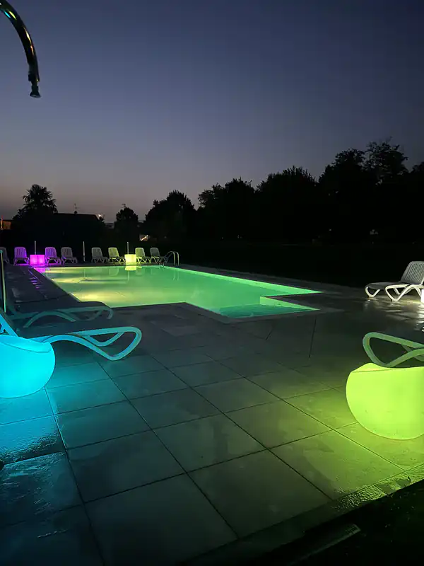 Piscina di notte dell'Agriturismo Al Buttasella con cubi colorati e luci immersive a Lavariano di Mortegliano (UD).